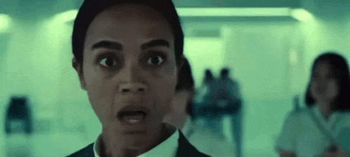 a close up of a woman 's face with a surprised look on her face in a hallway .