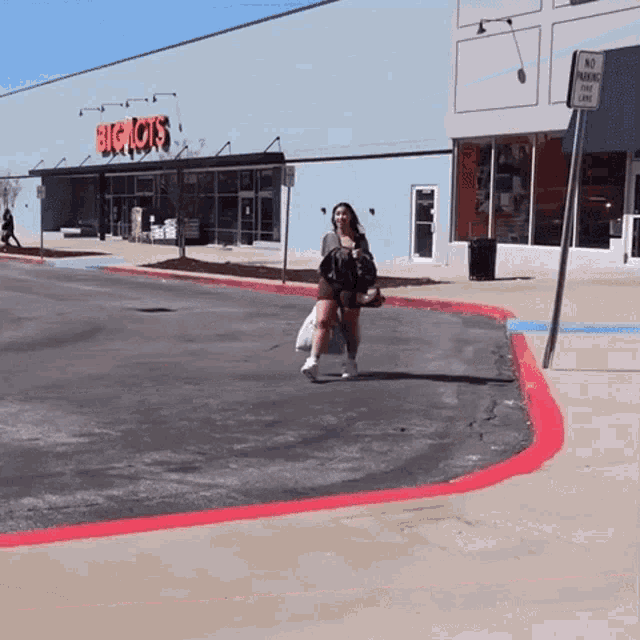a woman is crossing the street in front of a store called big lots