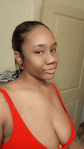 a woman wearing a red bra and earrings looks at the camera