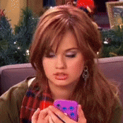 a woman in a plaid scarf is holding a purple phone