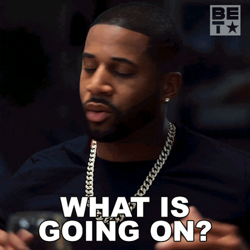 a man with a beard says " what is going on " while wearing a chain around his neck