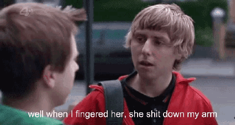 a young man in a red jacket is talking to another young man .