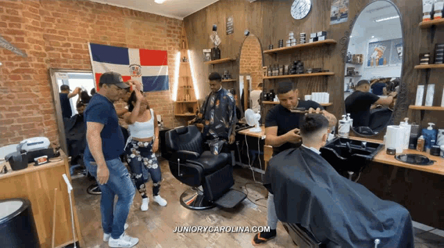 a man is getting his hair cut at a barber shop with juniorycarolina.com written on the bottom