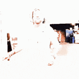 a man with a beard wearing a white shirt and a baseball cap is dancing in a hallway .