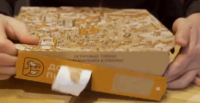 a person is opening a pizza box with a sticker on the side .