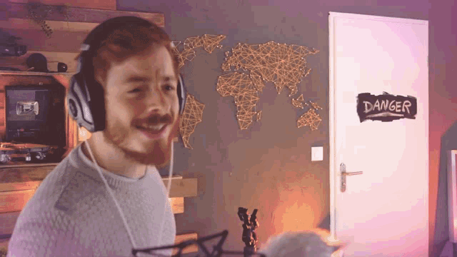 a man wearing headphones is standing in front of a door that says danger