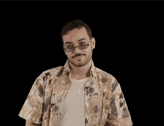 a man wearing sunglasses and a hawaiian shirt is making a gesture with his hands