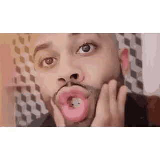 a man is making a funny face with a donut in his mouth .