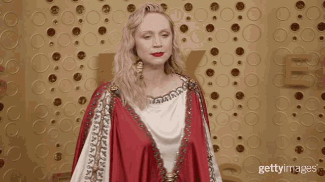 a woman in a red and white dress is standing in front of a wall with circles and the letter e on it