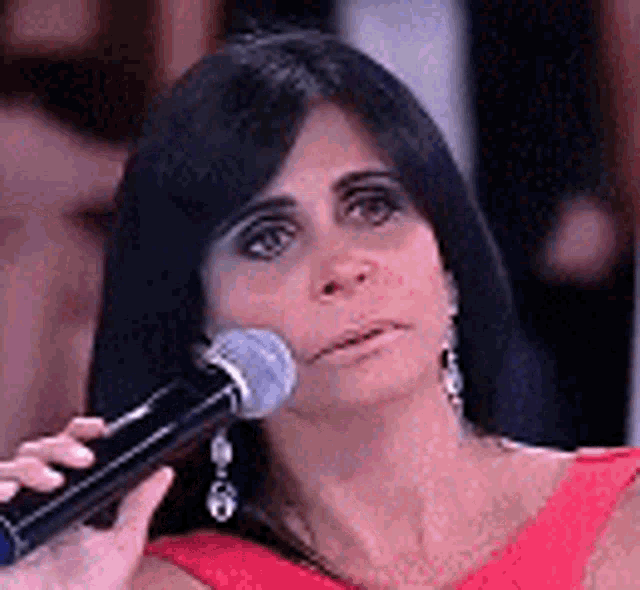 a woman in a red dress is holding a microphone in her hand .