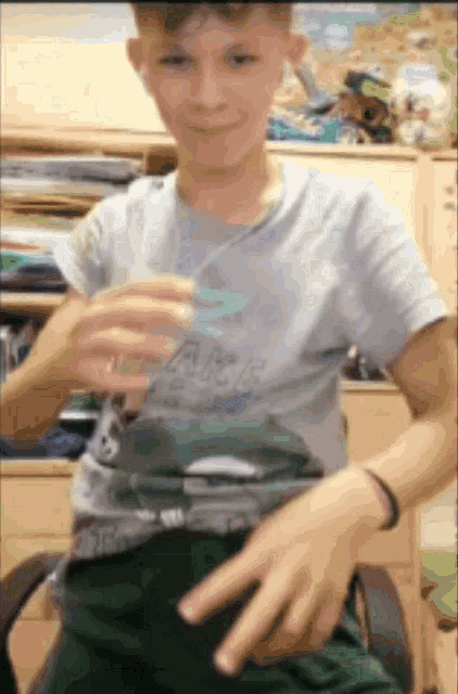 a boy wearing a shirt that says ' a few boys ' on it is sitting in a chair