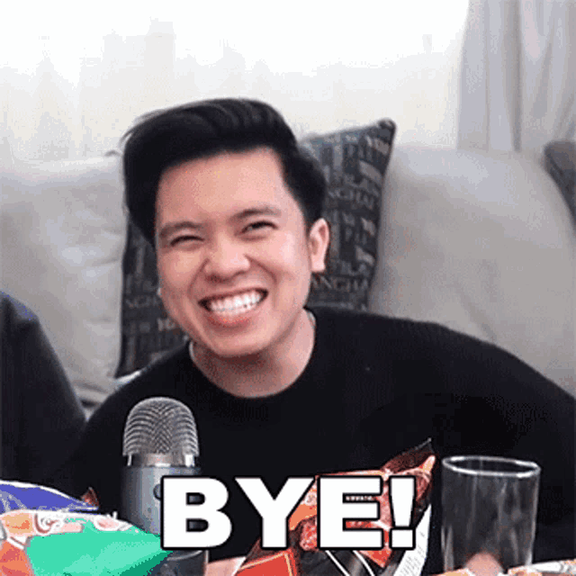 a man sitting in front of a microphone with the word bye in white letters