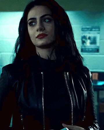 a woman in a black leather jacket is standing in a room .