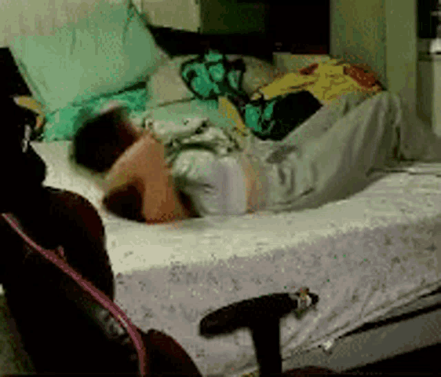 a person is laying on a bed with a chair in the background