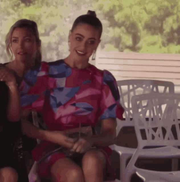 a woman in a pink dress sits next to another woman