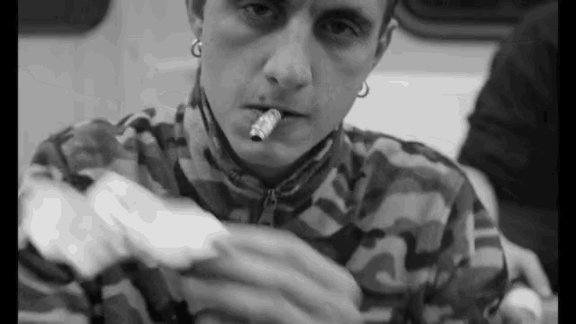 a man with a cigarette in his mouth wearing a camo jacket