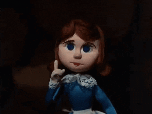 a doll with red hair and blue eyes is wearing a blue shirt and white apron