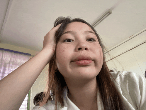 a girl with long hair is making a funny face with her hand on her head