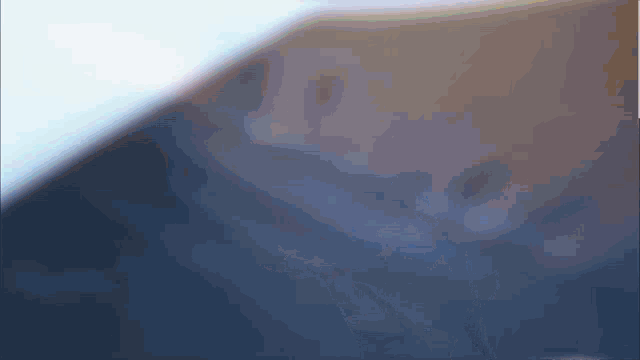 a blurred image of a person 's face with a blue sky in the background