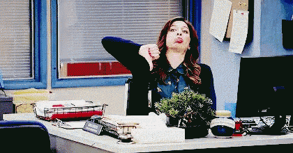 a woman is giving a thumbs down sign while sitting at a desk in an office .