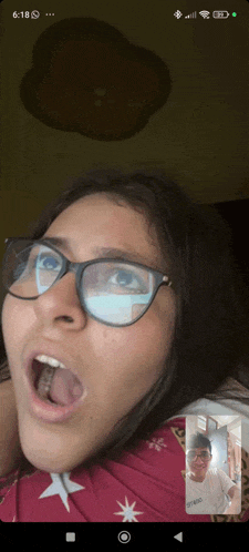 a phone screen shows a girl wearing glasses and a boy wearing glasses
