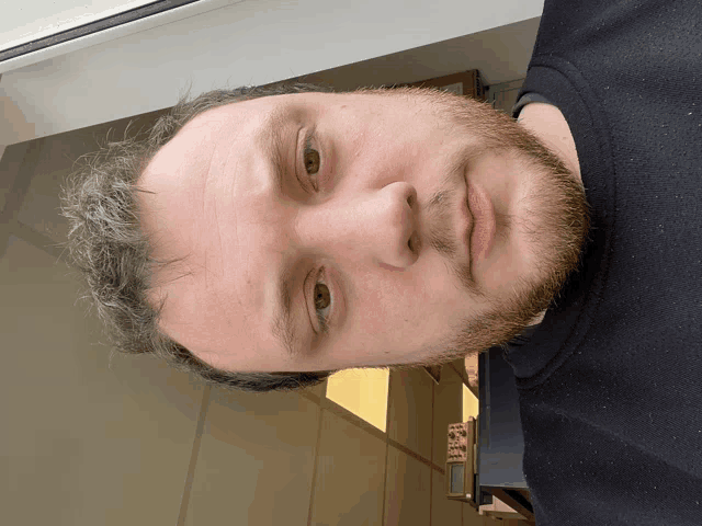 a close up of a man 's face with a beard and a black shirt