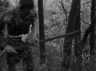 a black and white photo of a man holding a stick