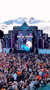 a crowd of people gathered in front of a stage that says new rwk on it