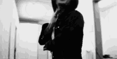 a man in a hooded jacket is standing in a hallway talking on a cell phone .