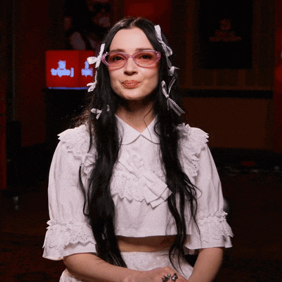 a woman wearing glasses and a white crop top is making a face