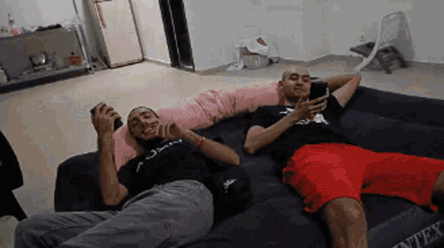 two men are laying on an inflatable couch that says intex on it