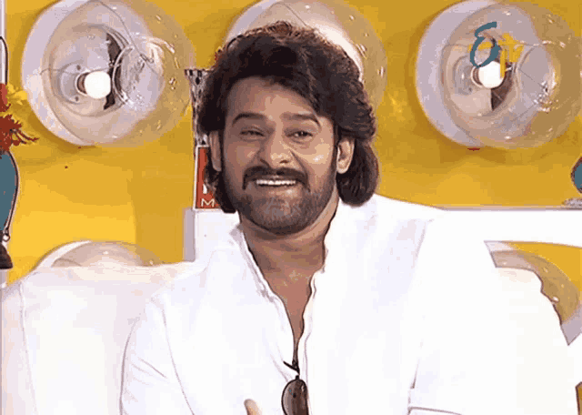 a man with a beard is smiling in front of a yellow wall