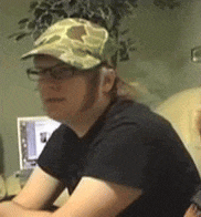 a man wearing a camouflage hat and glasses is sitting at a table .