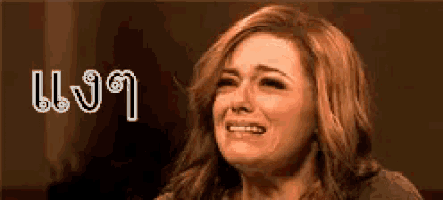 a woman is crying with her eyes closed in front of a sign that says ' l ' on it .