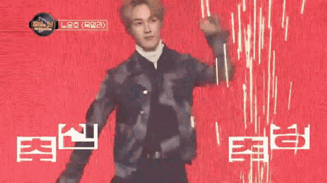 a man in a black jacket is dancing on a red background with chinese writing .