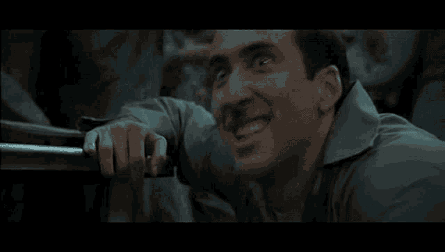 a man is laughing while holding onto a railing in a movie scene .
