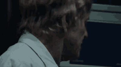 a man in a white shirt and tie is standing in front of a computer screen .
