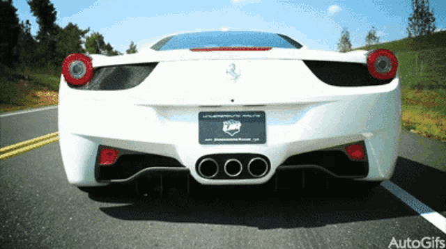 a white ferrari is driving down the road
