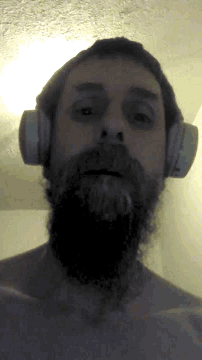 a man with a beard wearing headphones looks down