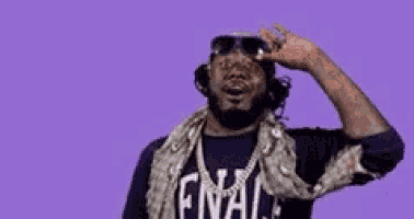 a man wearing sunglasses and a shirt that says final is standing in front of a purple background