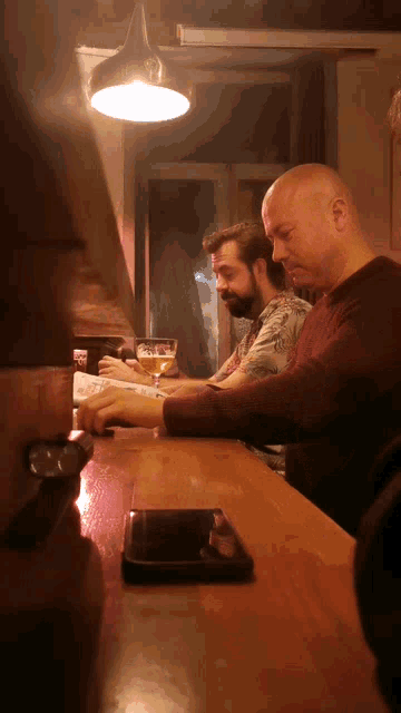 a man sits at a bar looking at a menu and drinking a beer