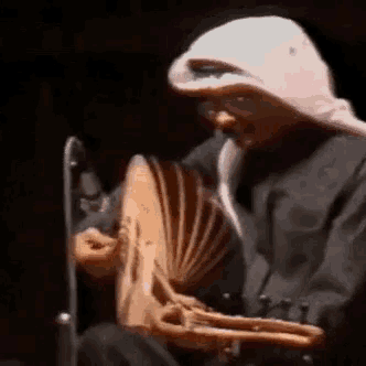 a man wearing a white head scarf is playing a fan
