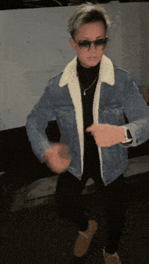 a man wearing sunglasses and a denim jacket dancing