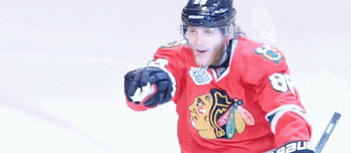 a hockey player with the number 88 on his helmet is pointing to the camera .