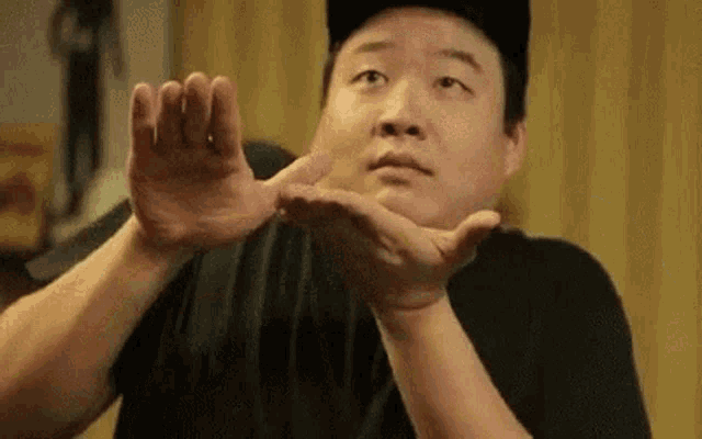 a man in a baseball cap is making a funny face while holding his hands together .
