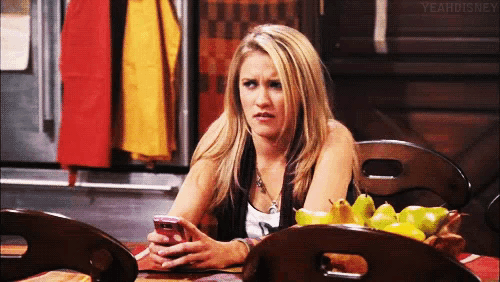 a woman sits at a table looking at her cell phone