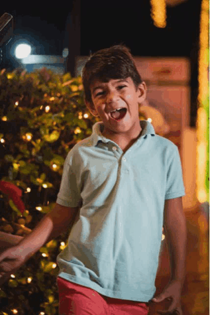 a boy in a blue shirt and red shorts is laughing