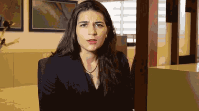 a woman in a black jacket is making a face