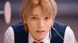 a close up of a young man wearing a suit and tie with headphones .