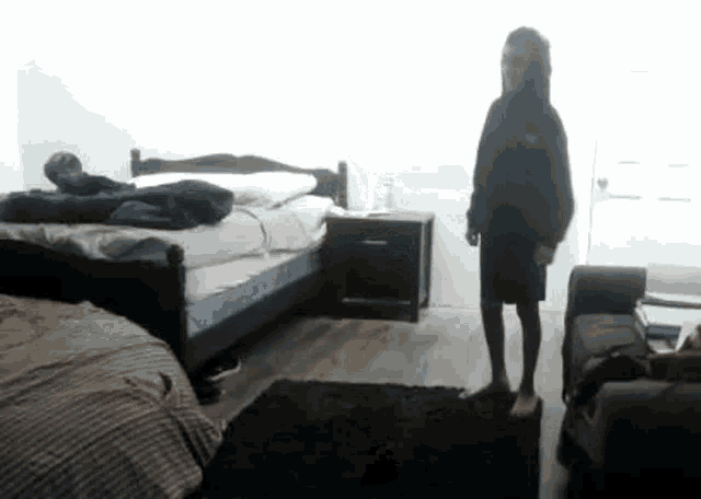 a person is standing in a bedroom next to a bed and couch .
